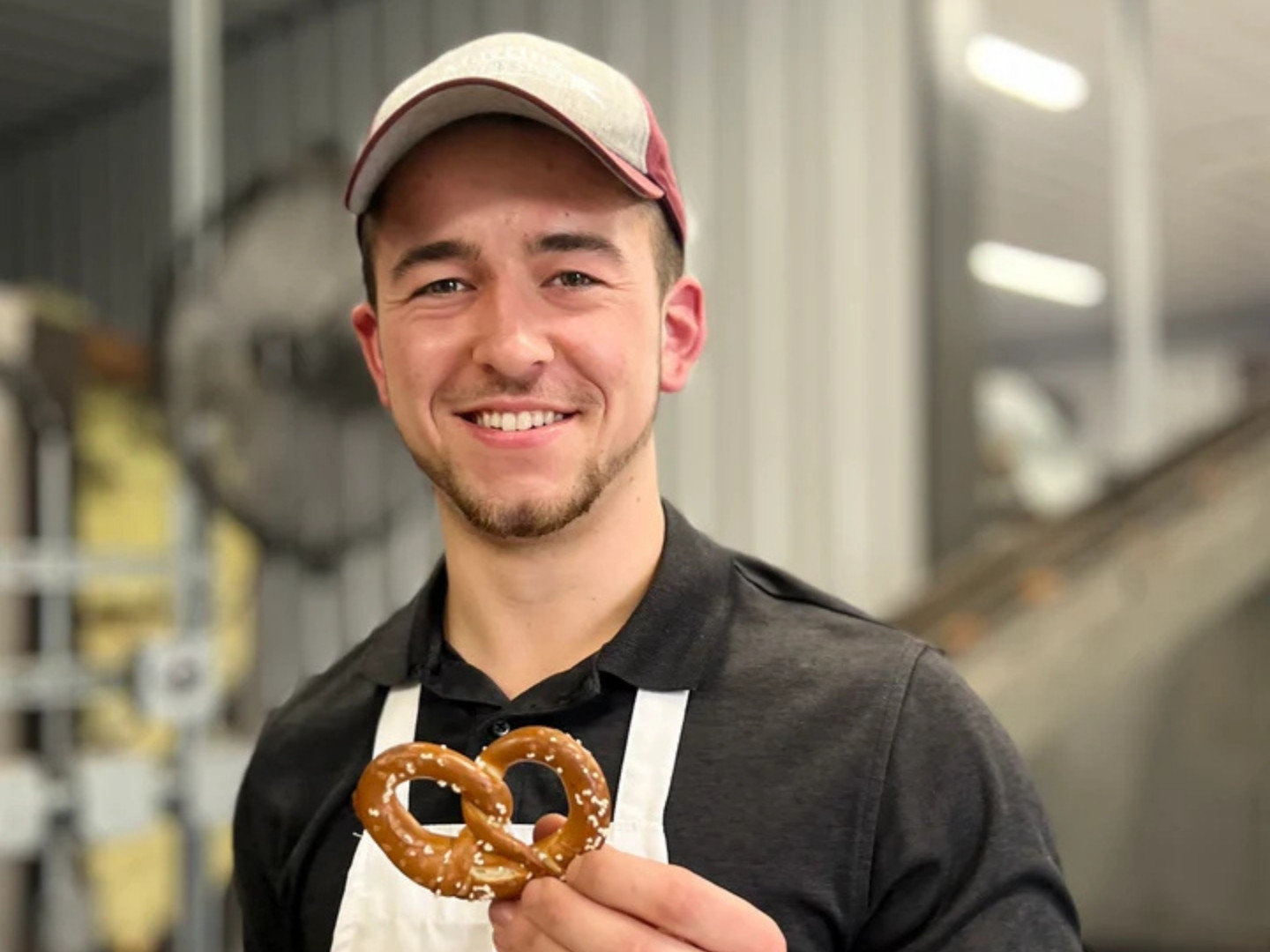 Josiah Martin of Martin’s Pretzel Bakery smiles while holding a handmade pretzel.